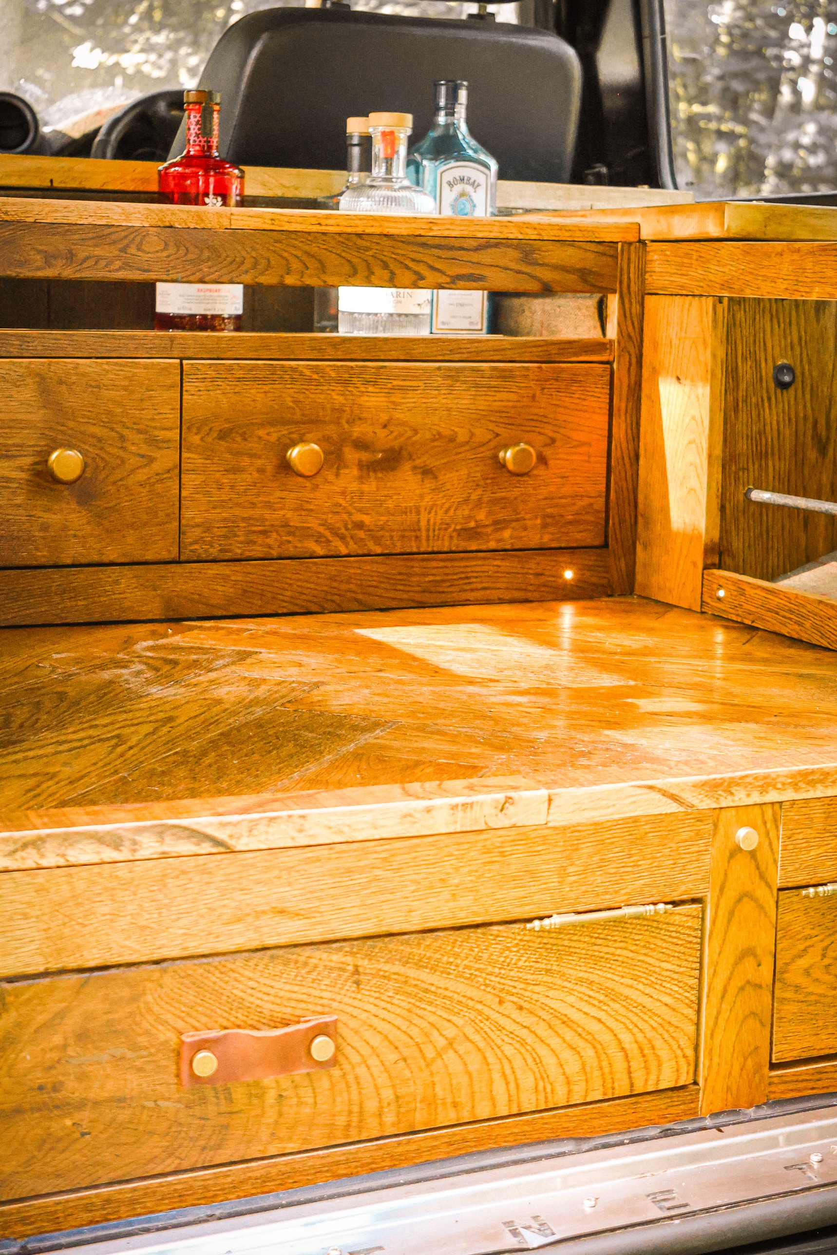 Oak drawers and cabinetry inside the Defender 90, with brass knobs and leather pulls